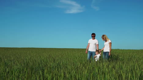 Mother-father-and-son-walk-in-the-field-with-spikes-in-white-t-shirts-and-jeans-smiling-cheerfully-at-each-other