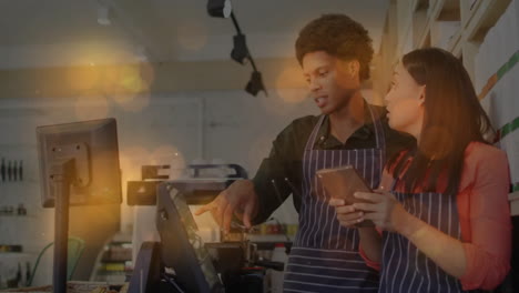 two coworkers tapping pos terminal and swiping tablet in bakery cafe, showing floating sales chart