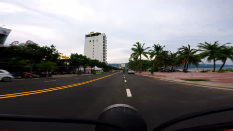 riding a scooter along the busy road near my khe beach in da nang, vietnam - pov