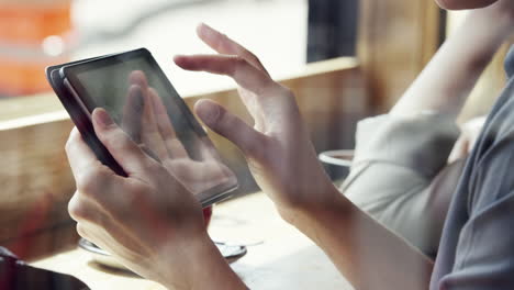 closeup woman hands using ipad touchscreen tablet display in cafe