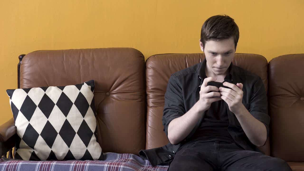 소파 에 스마트폰 을 사용하는 젊은 남자