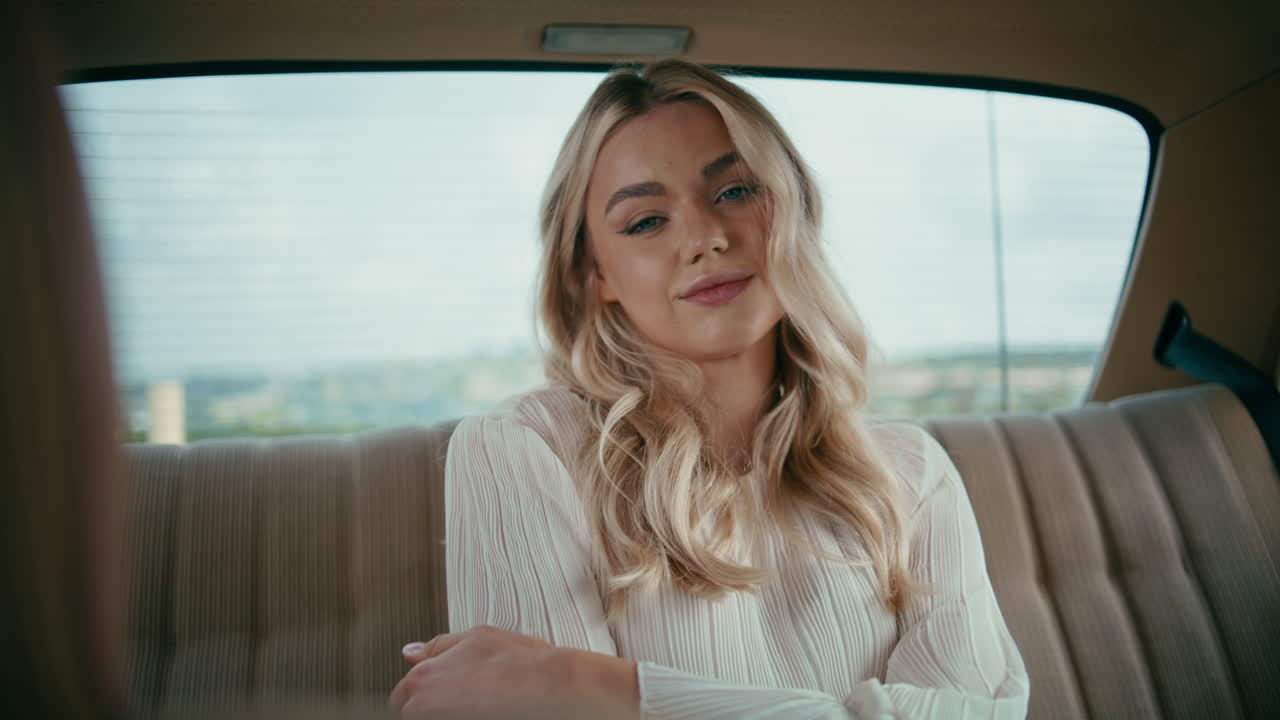 자동차 뒷좌석에 앉아 있는 여성 관광객이 카메라를 가게 바라보고 있습니다. 차에서 포즈를 취하는 소녀