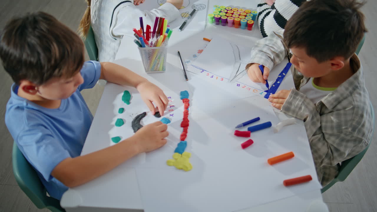Excited kids enjoying art lesson in school closeup. Boys sculpting plasticine