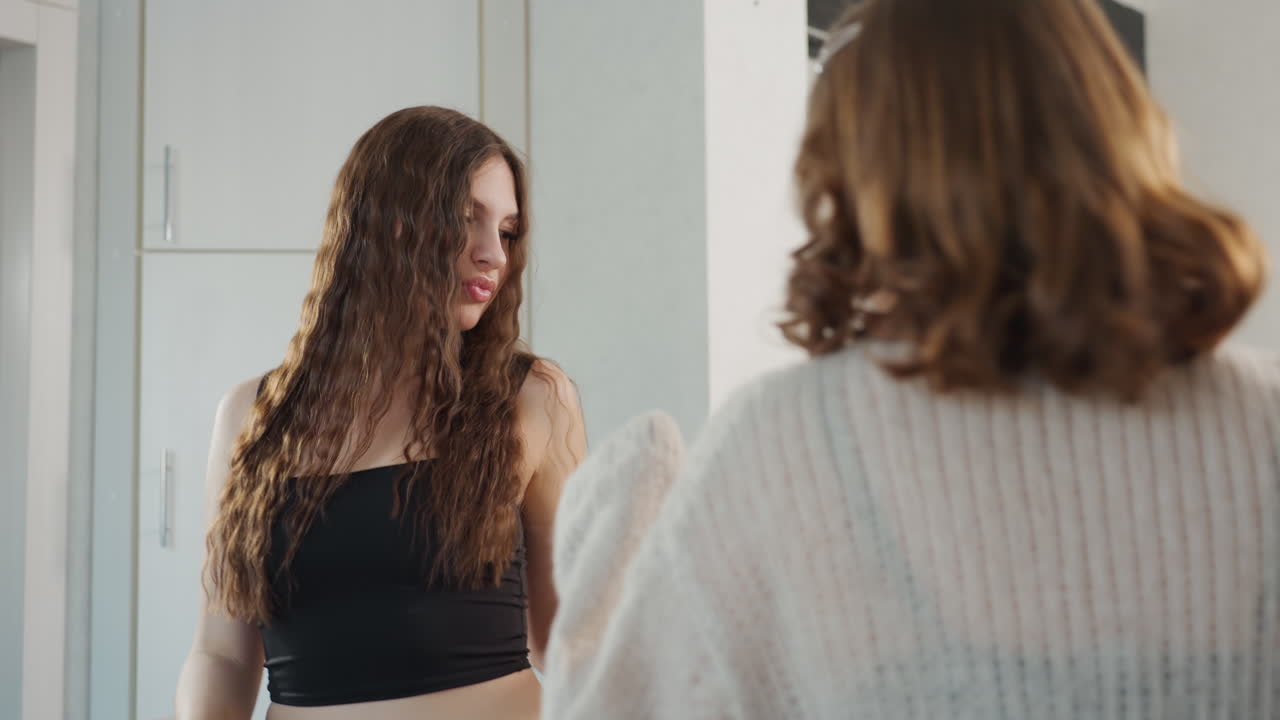 Young White Woman In Kitchen Styling And Arguing With Friend, Tense Hair Check, Curly Locks Examined By Companion, Expressive Gestures, Intimate Domestic Scene With Modern Cabinets And Natural Light