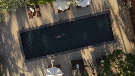 aerial drone birdseye view shoot a man swimming in the pool nice sunshine with camera rotate a circle_dalat vietnam 22aug2020_4k 24fps