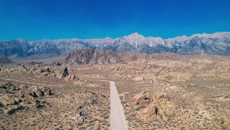 Alabama-Hills-En-Lone-Pine-California-4.000-Imágenes-De-Drones-Giran-La-Cámara-Hacia-La-Izquierda-Y-Empujan-Hacia-Adelante-De-La-Carretera-De-La-Película-Con-El-Monte-Whitney-En-El-Fondo