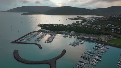 airlie playa bahía laguna mar de coral marina drone aéreo niebla amanecer nubes de lluvia corazón de la gran barrera de arrecifes whitsundays whitehaven muelle yates veleros círculo movimiento a la izquierda