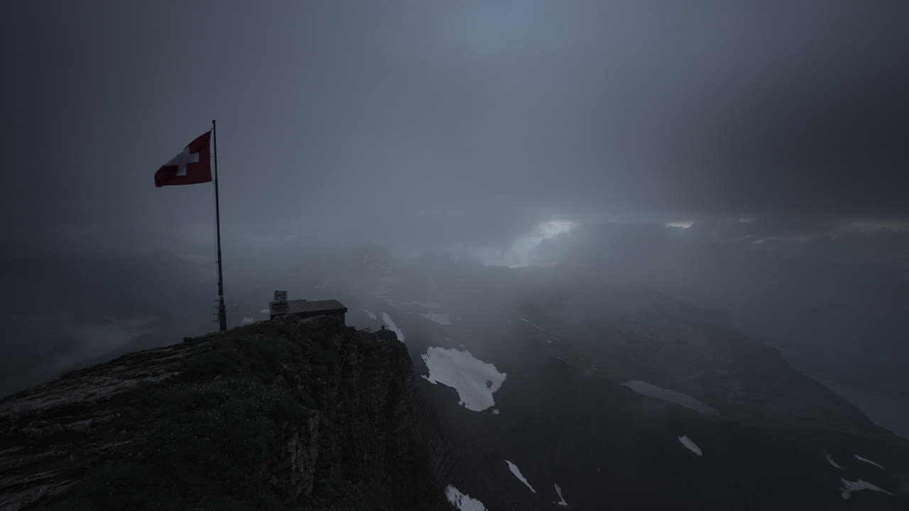 Swiss Alps Mountain Peak with Flag and Cabin in Foggy Weather