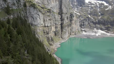 vertical mountain cliffs reflecting in the light blue water of the oeschinesee in switzerland