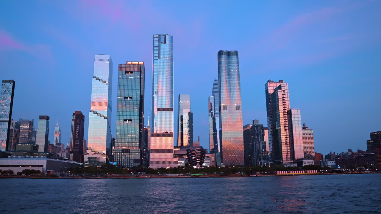 Nova Iorque, EUA, 9 de agosto de 2025: Horizonte de Hudson Yards e Vessel ao anoitecer, vistos do rio. Arranha-céus modernos de Hudson Yards, incluindo The Vessel, refletidos no Rio Hudson durante a hora azul.