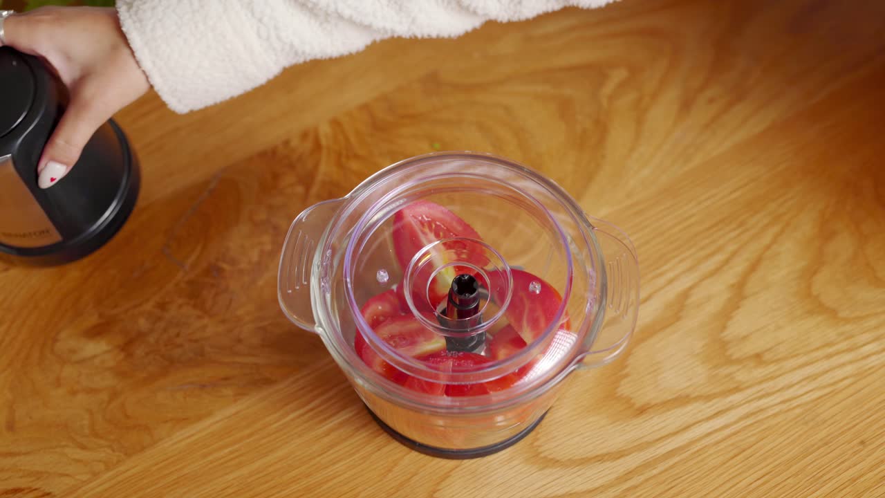 Pomodori che entrano in un tritatutto compatto, ripresa statica ravvicinata.