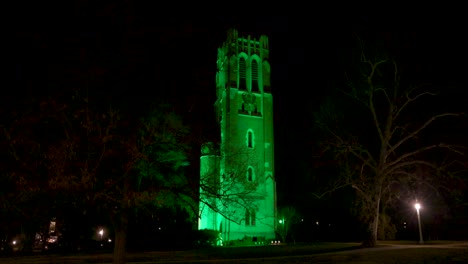 beaumont tower on the campus of michigan state university lit up at night in green in honor of the victims of the february, 2023 mass shooting with video stable establishing shot