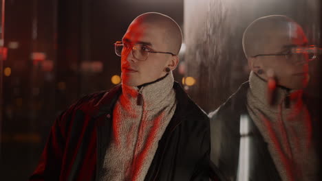 stylish bald man with glasses and ear gauges at night