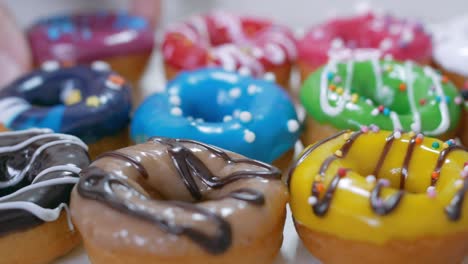 the box contains several beautiful donuts, doused with multi-colored fruit icing and chocolate. two lush donuts are added to them. sweets close-up. junk food