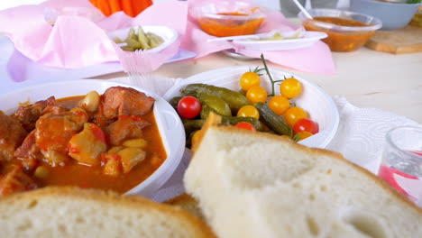 Goulash-with-fresh-bread-and-pickles,-served-in-plastic-containers