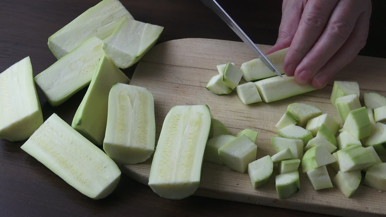 Woman holding kitchen knife, chopping peeled zucchini. Healthy eating concept.