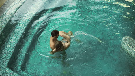 Pareja-En-La-Piscina-Bañándose-Juntos.-Vista-Superior-Familia-Joven-Relajándose-En-La-Piscina.