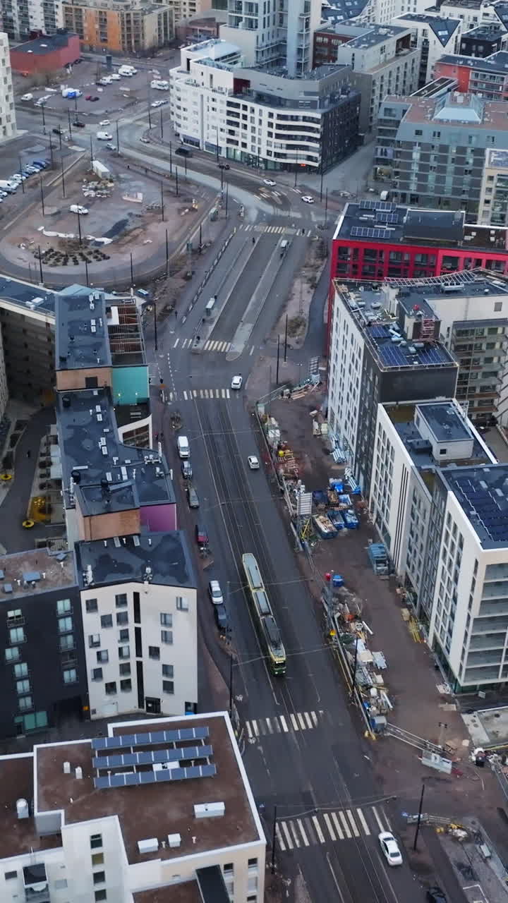 Vertical drone shot tracking a tram on the streets of Jatkasaari, cloudy Helsinki