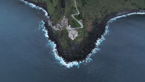 Drone-tops-down-Portugal-travel-destination,-Arnel-Lighthouse-in-San-Miguel-sea-view,-green-cliff-at-Azores-volcanic-archipelago