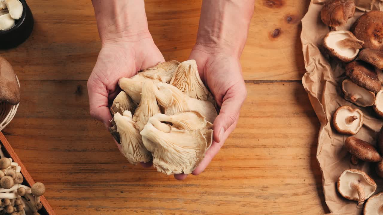 Hands Holding Fresh Mushrooms on Wooden Table