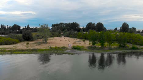 A-couple-walks-up-a-grassy-hill-away-from-a-lake