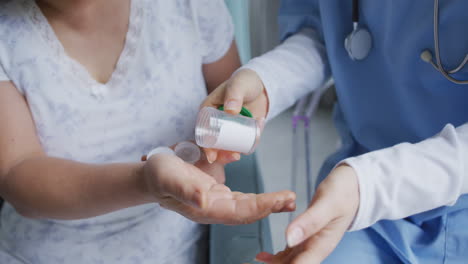 midsection of asian female doctor helping female patient take her medication at hospital