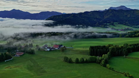 aerial drone shot over village cottages with mountain range in the background during morning time