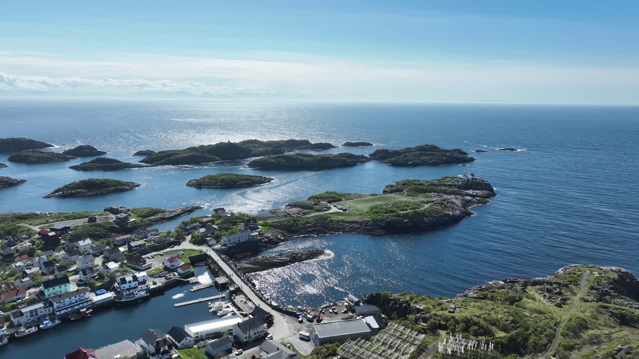 Forward aerial over Henningsvaer in Lofoten showing ocean, coastline and famous football field