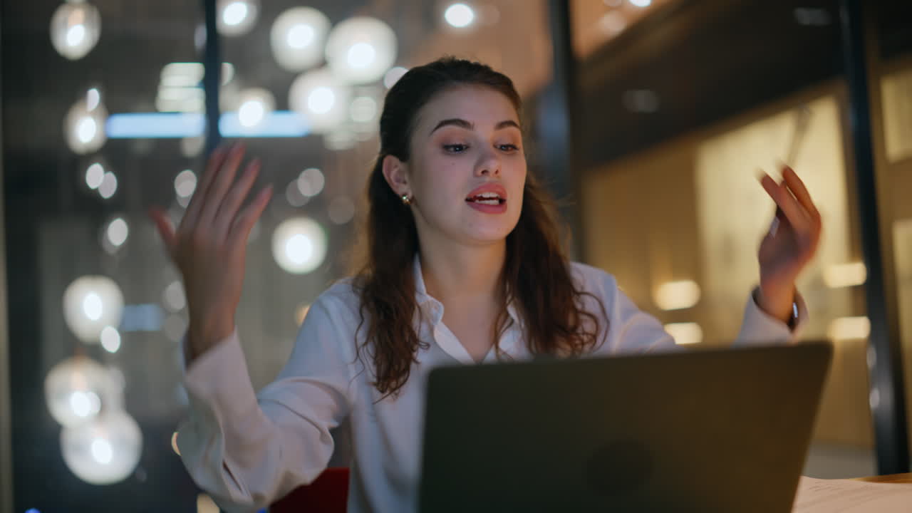 Primo piano di un amministratore delegato di successo che parla durante una riunione virtuale e guarda il portatile in ufficio di sera