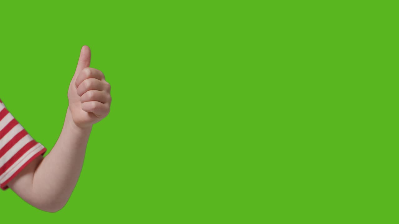 Close Up Of Young Boy Giving Thumbs Up Gesture To Camera Against Green Screen