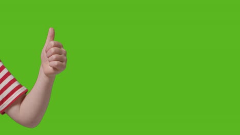 primer plano de un niño dando pulgares hacia arriba gesto a la cámara contra la pantalla verde