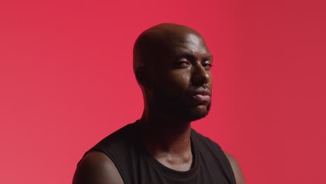 studio portrait shot of male athlete wearing sports vest against red lit background