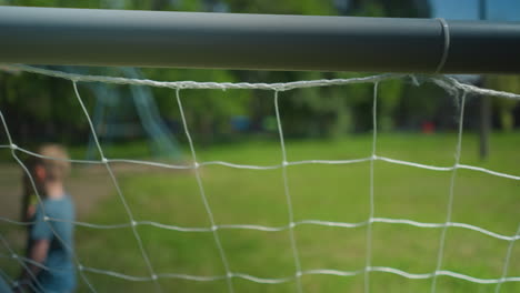 close-up of a soccer goal net with a blurred view of a young boy walking away in the background