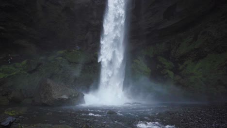 a waterfall in iceland, surrounded by tall cliffs and crashing onto rocks- slow motion