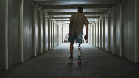 person with prosthetic leg walking through an underground tunnel