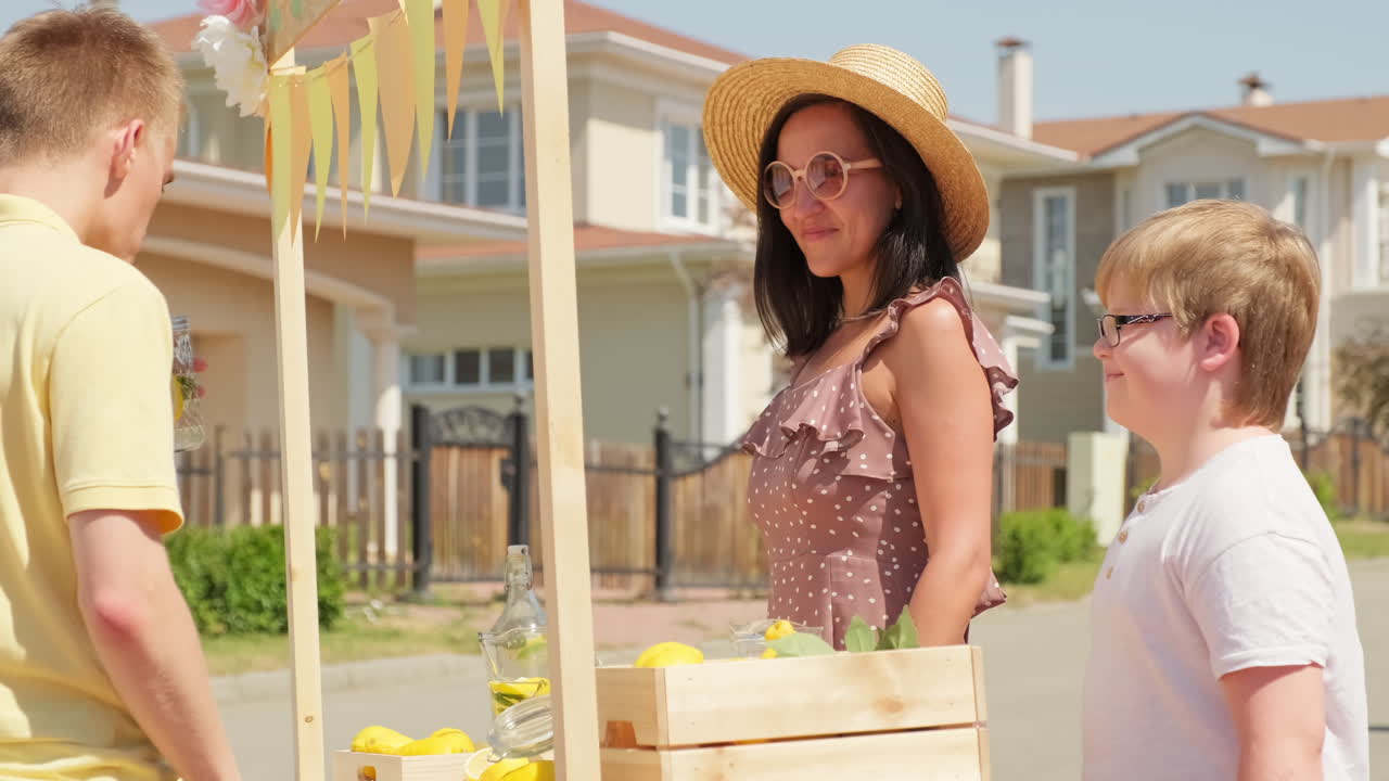 Boy Buying Lemonade Outdoors In Summer