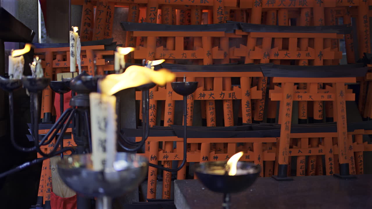 Fushimi Inari Shrine in Japan with candles flickering gently, illuminating inscriptions and creating a peaceful atmosphere. Translation on candle: ''Inari - God of Rice''