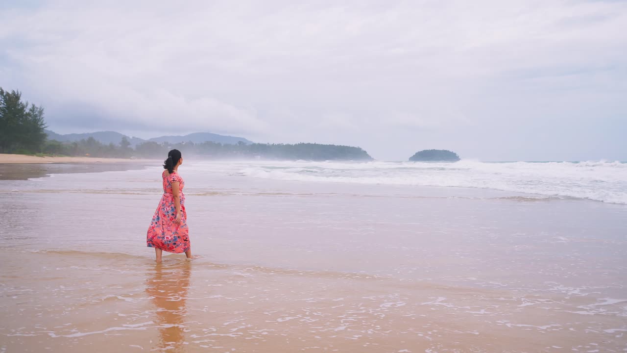 해변을 걷고 바다 공기의 아름다움에 감탄하는 젊은 아시아 여성