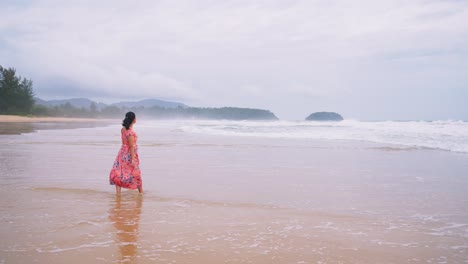 young asian woman walking on the beach and admiring the beauty of the sea air