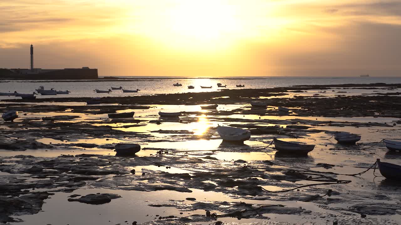 inclinación lenta hacia arriba sobre el océano con reflejos y siluetas de puesta de sol