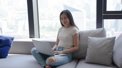 woman working on laptop at home with city view