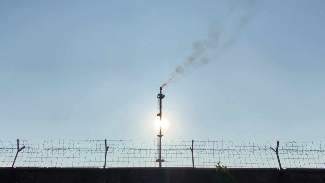 산업 지역의 유선 울타리 벽, 가스 플레어 연소 방출 굴뚝