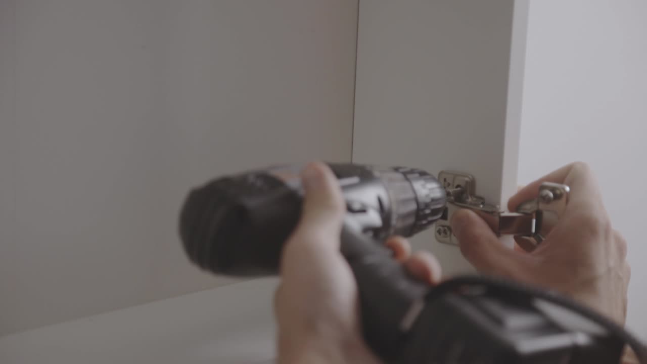 전기 스크루드라이버 로 캐비 ⁇  힌지 를 설치 하는 사람 - 근접