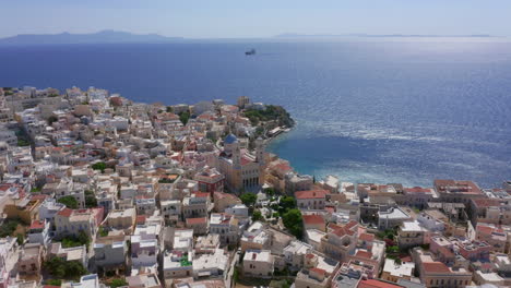 Aerial:-Slow-panoramic-drone-shot-of-Asteria-Beach-in-Ermoupoli-of-Syros-island,-Greece-on-a-sunny-day