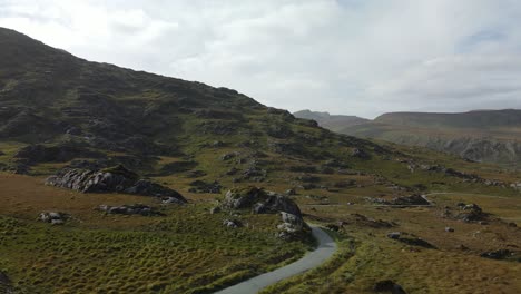 Orange-coloured-ferns-on-hills-and-mountains-in-Kerry,-Ireland-and-winding-narrow-road