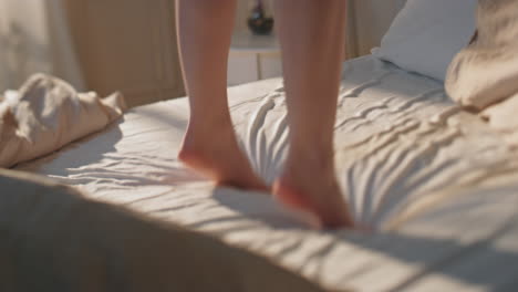 excited legs jumping bed in morning sunlight closeup. happy slim woman dancing