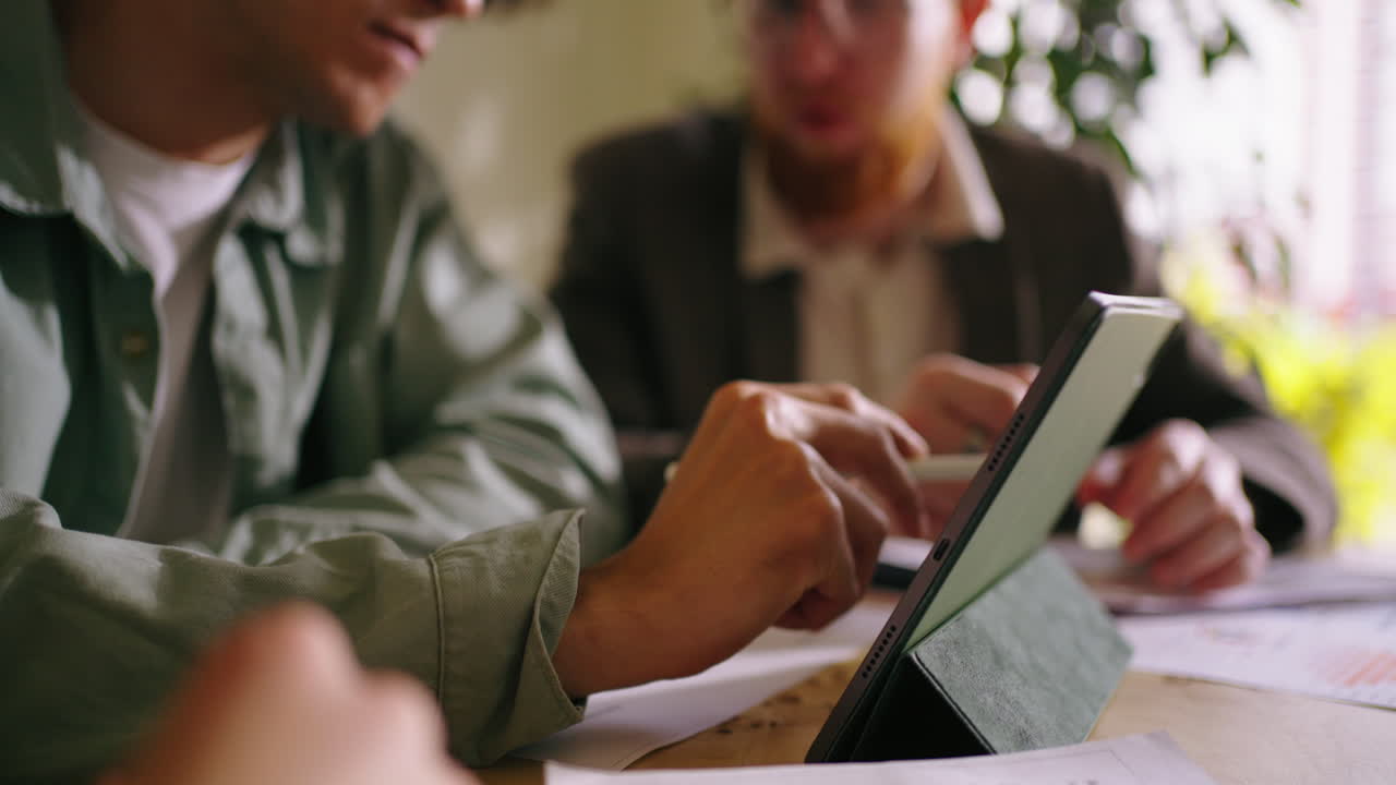 Two businessmen are discussing a project on a tablet during a meeting at a desk