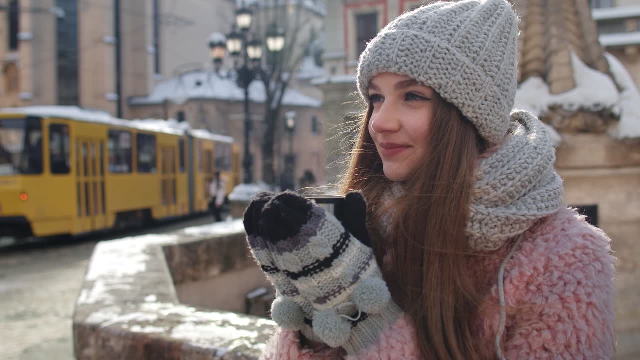 휴가 중 도시 거리를 둘러보는 컵에 뜨거운 음료를 가진 세련된 여성 여행자