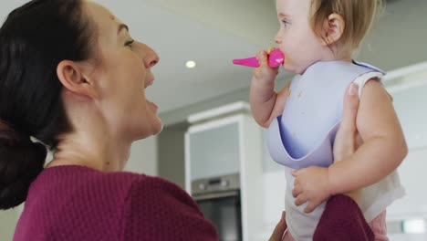 madre caucásica sosteniendo a su bebé después de alimentarla en casa