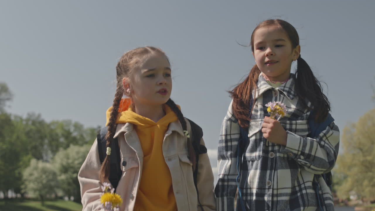 Two Young Girls Walking Hand-in-Hand in a Park